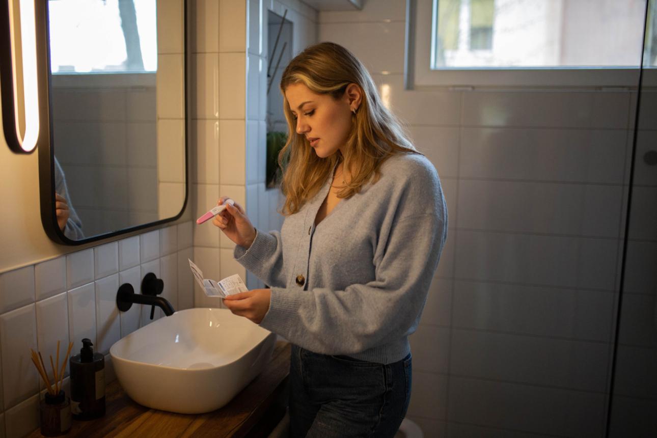 A young woman reading instructions for a pregnancy test